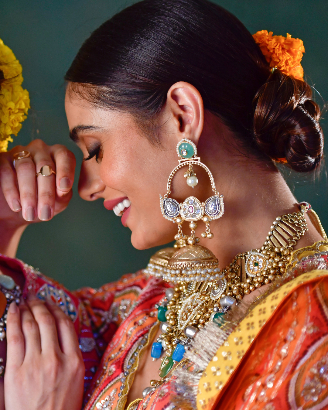 An indian woman wearing golden statement jhumka earrings. 