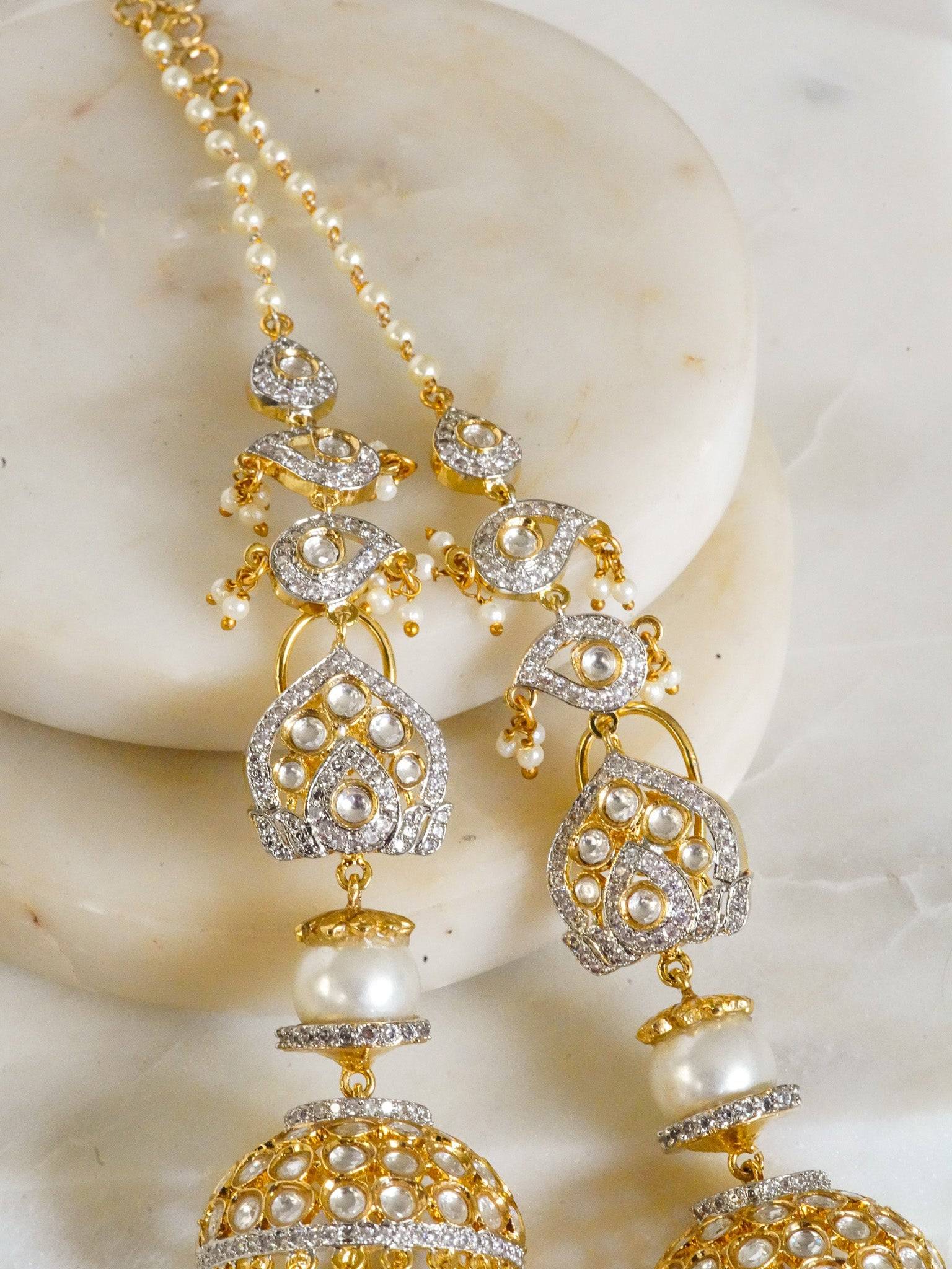 Aniva earrings with Moissanite Polki stones, white diamante accents, and dangling faux pearls, featuring multiple layers and attached pearl earring chains for added allure.
