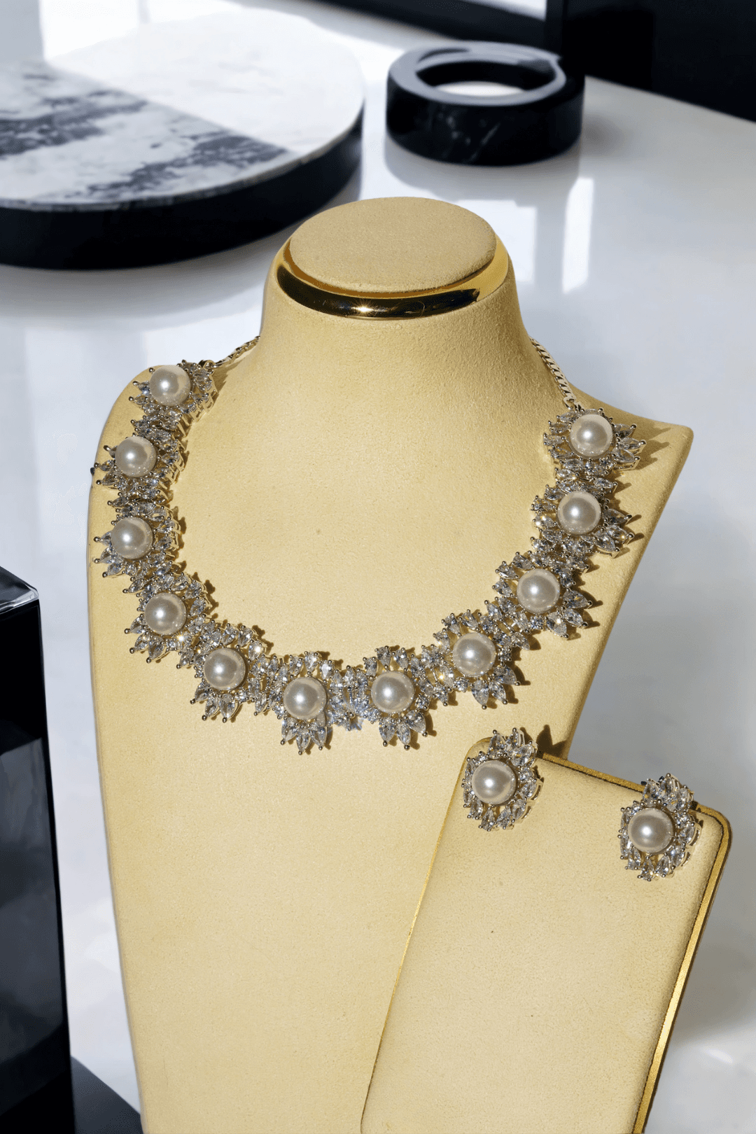 Mayesha Rhodium-Plated Pearl Cluster Necklace and Earring Set with luminous pearls and sparkling cubic zirconia clusters displayed on a cream jewelry stand.